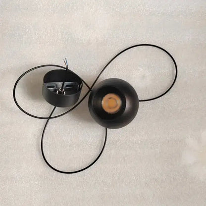 Minimalist black spherical pendant light with die-cast aluminum and acrylic lamp holder featuring visible led bulb