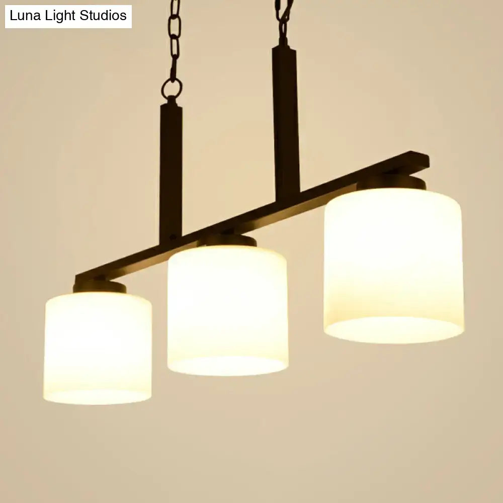 Black metal island lighting fixture with three opal frosted glass cylindrical shades and minimalist metal frame design