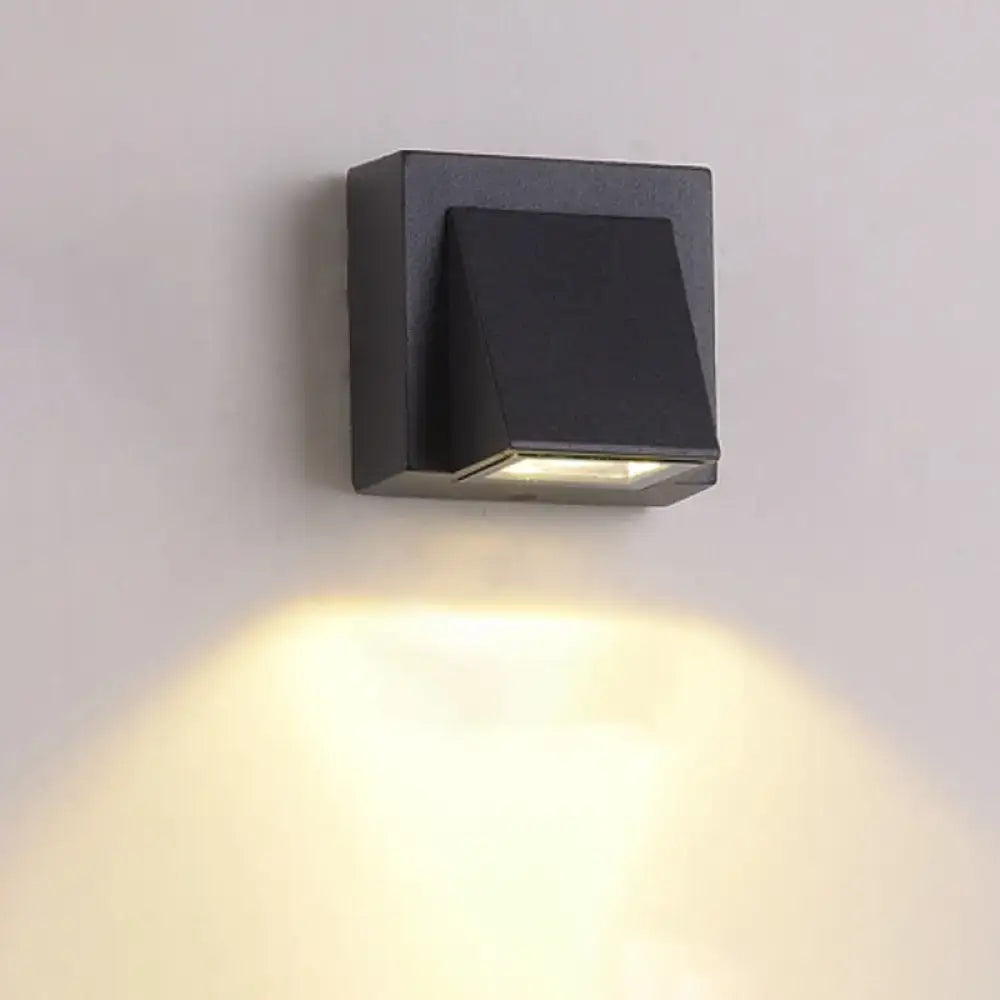 Black square wall lamp with minimalist triangle aluminum flush design emitting warm yellow light for corridor use
