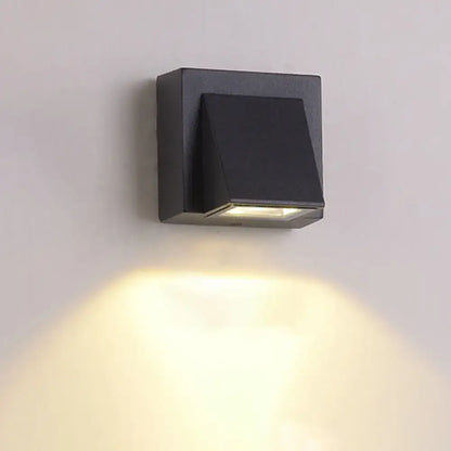 Black square wall lamp with minimalist triangle aluminum flush design emitting warm yellow light for corridor use