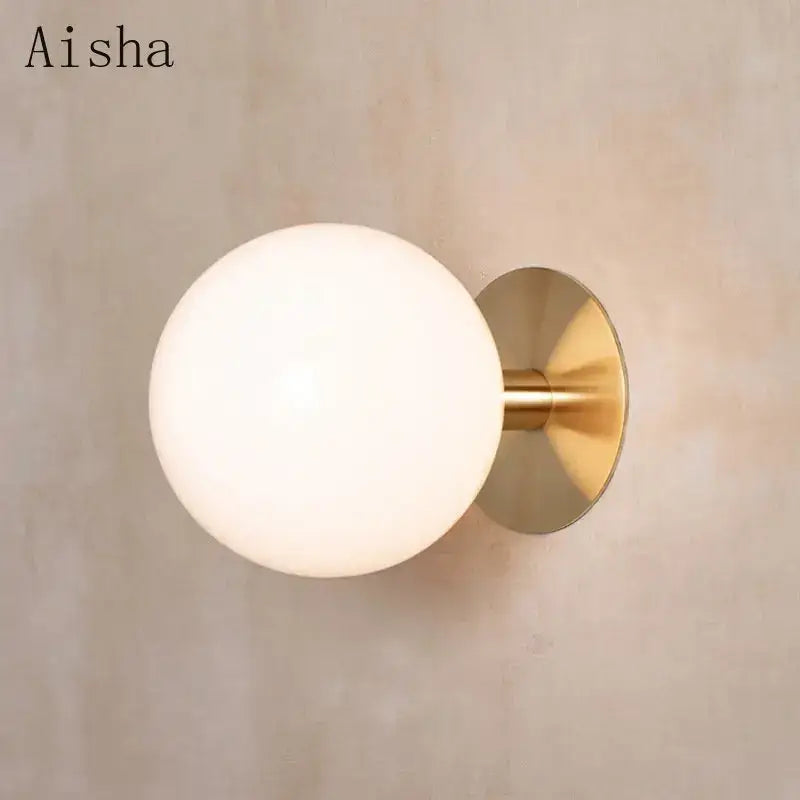 Aisha brand wall lamp with a frosted white glass globe and polished brass hardware lighting fixture by decorbites gold