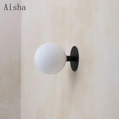 Minimalist black wall lamp with a frosted white glass globe lighting fixture by Aisha brand for bedroom decorbites gold