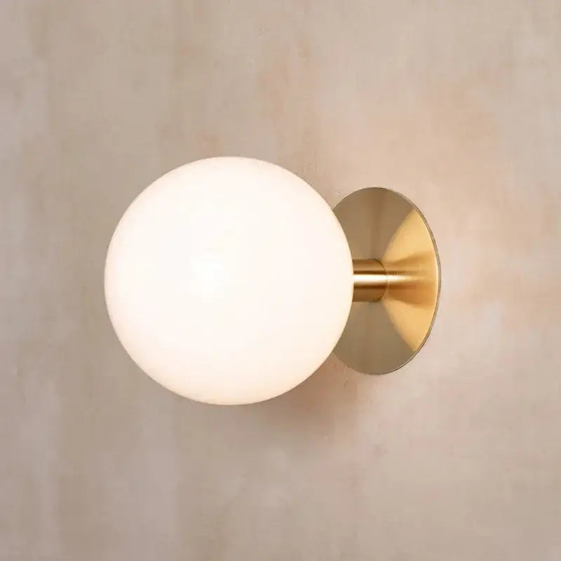Gold-toned wall lamp with frosted glass globe lighting fixture by decorbites for minimalist bedroom decor