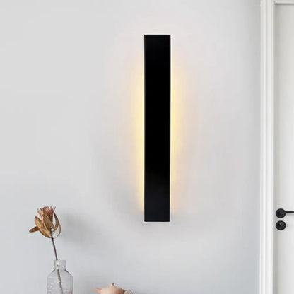 Black rectangular direct wired wall sconce with aluminum shade and warm ambient lighting for bedroom use