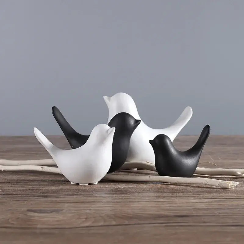 Set of minimalist black and white ceramic bird figurines arranged on driftwood for living room decor figurine set