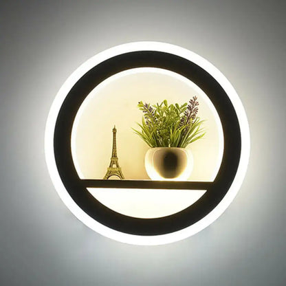 Minimalist black and white circular led wall sconce with shelf featuring a glowing led ring holding decorative items