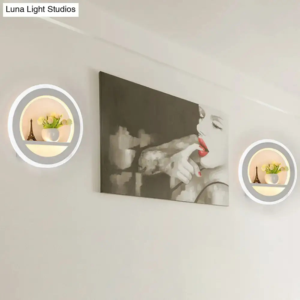 Minimalist black and white circular led wall sconce with sleek white frame soft glowing ring and inner shelf holding decor