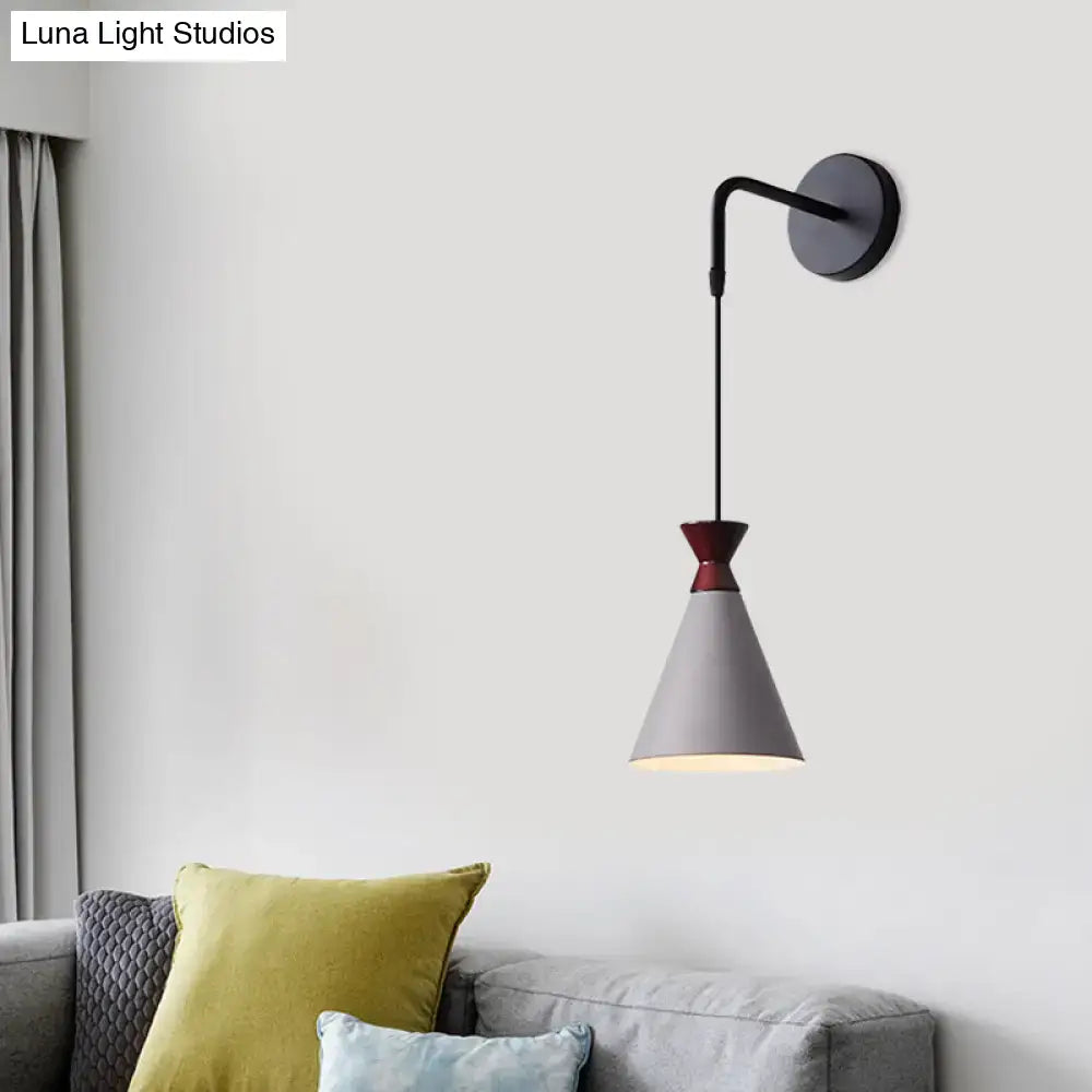 A minimalist iron conical wall light with a matte gray shade, burgundy top, and black metal arm for bedroom use