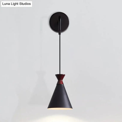Black iron conical wall light with red accent band and matte finish suspended from circular mount for bedroom use