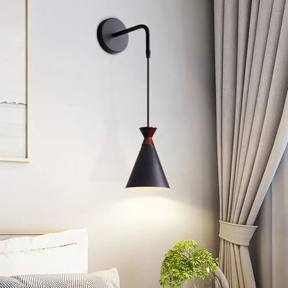 Minimalist black iron conical wall light with red accent on shade top designed as a bedroom wall light sconce