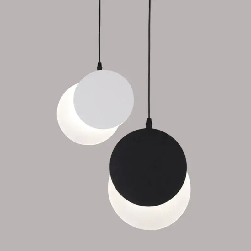 Minimalist black and white crescent moon pendant chandelier with two circular matte shades hanging on black cords by decorbites