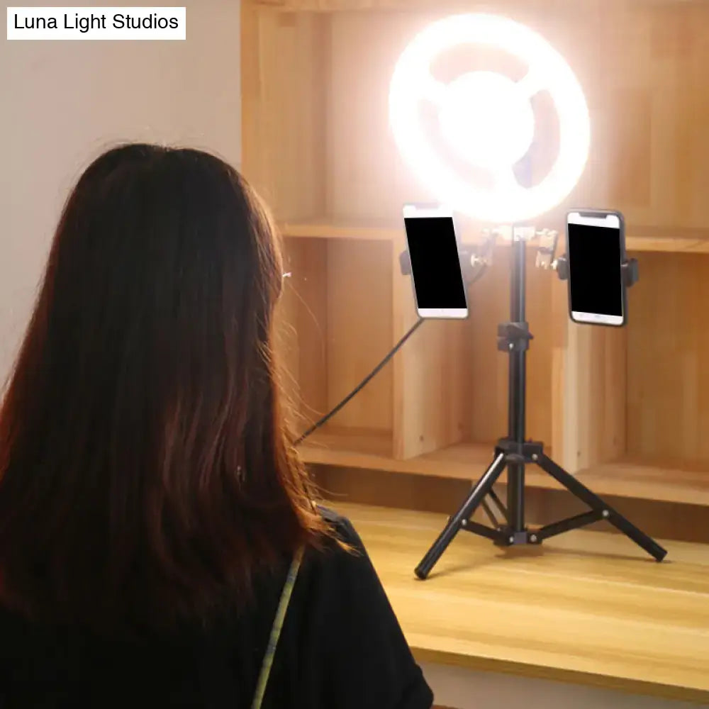 Black minimalist led ring light inch fixture with phone holder mounted on tripod holding two smartphones in bedroom setup