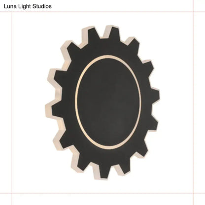 Black gear-shaped wall mirror with gold-toned inner rim complements minimalist black white led wall sconce with warm white light