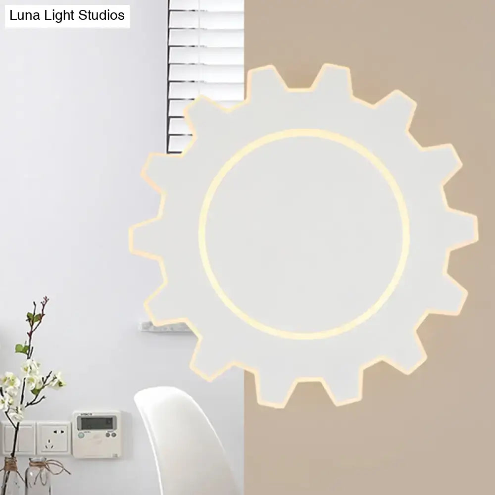 A modern white gear-shaped led wall sconce with a glowing yellow ring providing warm white light for bedroom use