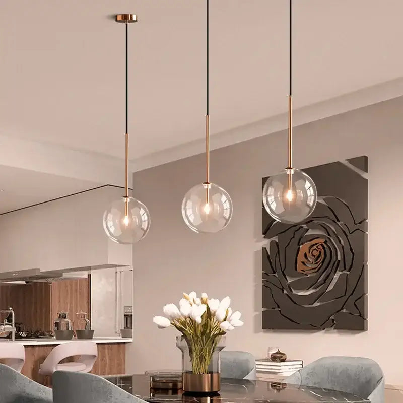 Three modern pendant lights with clear glass ball shades and brass-finished rods for dining room decorbites clear glass