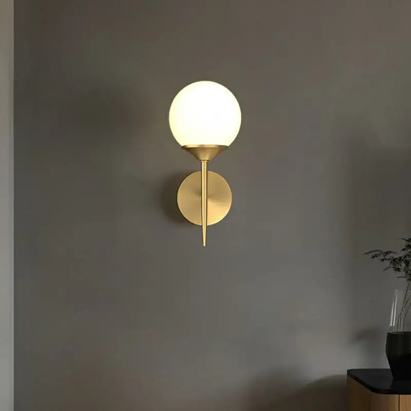 A sleek minimalist brass led wall lamp with frosted glass globe ideal for modern dining room lighting