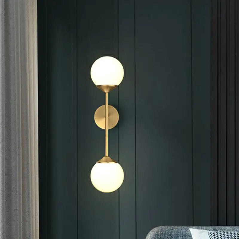 Gold-toned minimalist brass led wall lamp with two frosted glass globe shades for dining room lighting