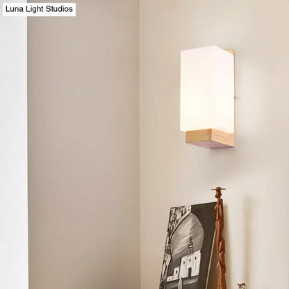 Minimalist brass and glass geometric wall sconce with frosted white diffuser and light wood accents for bedroom lighting