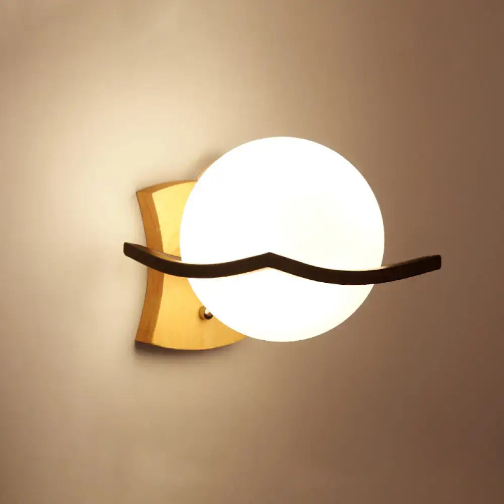 Minimalist brass and glass geometric wall sconce with gold-toned metal, frosted white glass shade, and black curved accent