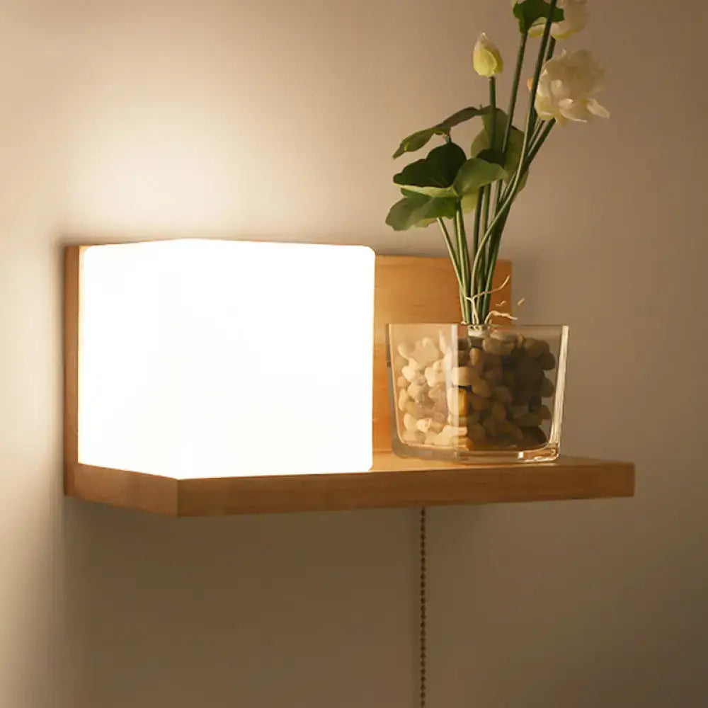 Minimalist brass and glass geometric wall sconce with a wooden shelf and glowing white light holding white flowers