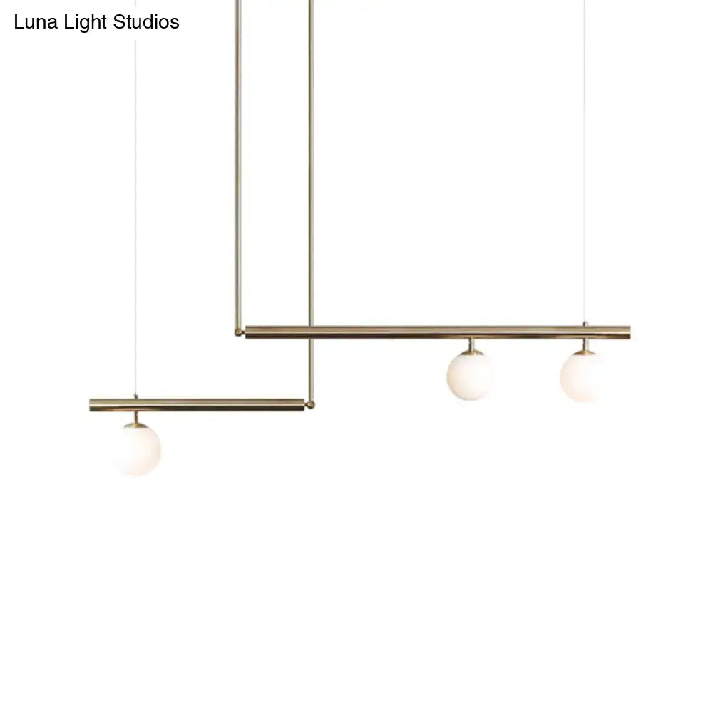 Minimalist ceiling light with three white glass globe shades and brass rods for kitchen island lighting