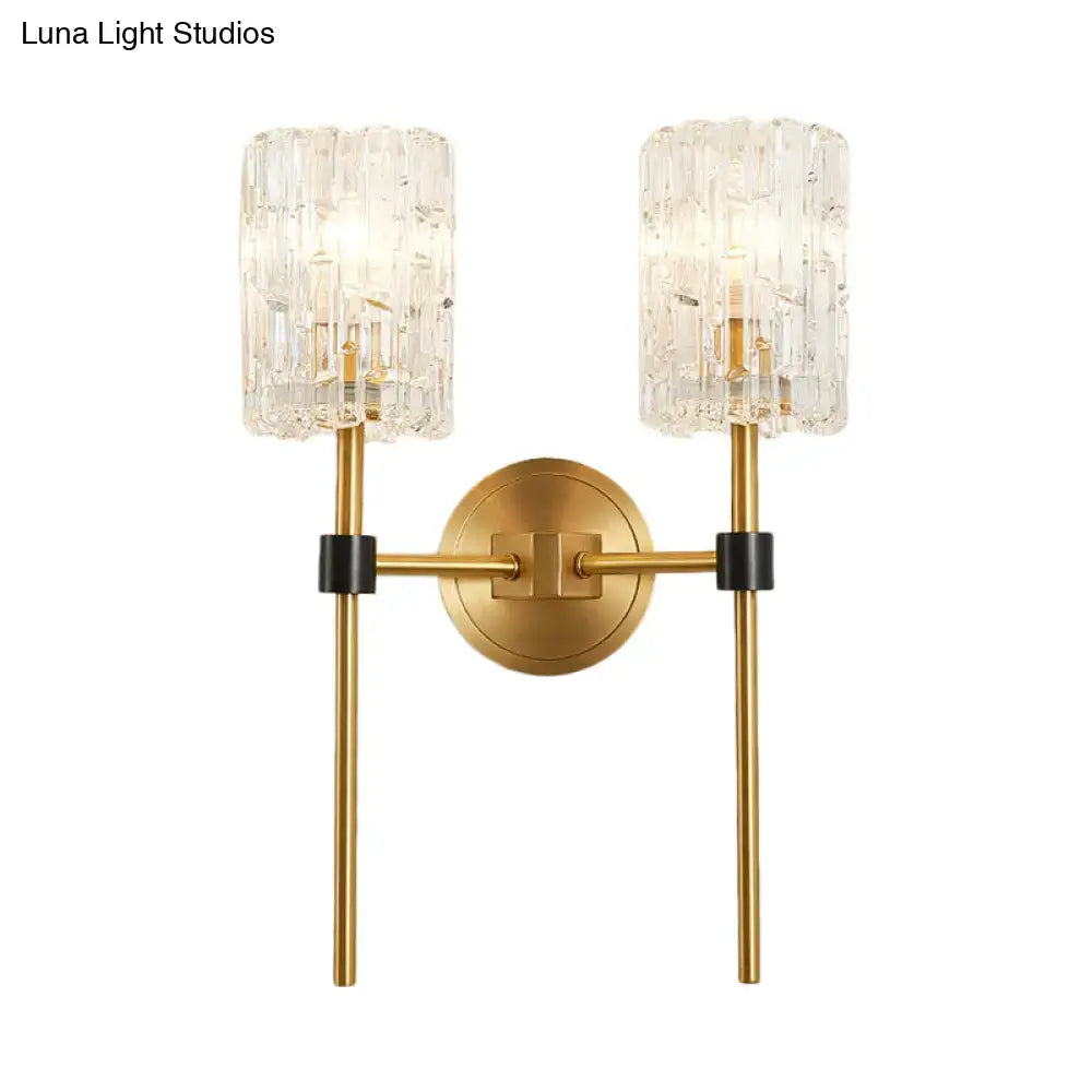 Minimalist brass wall sconce with gold-toned textured crystal cylindrical shades and black accents for living room lighting