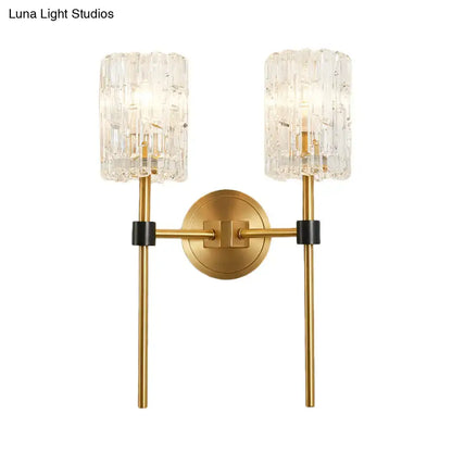 Minimalist brass wall sconce with gold-toned textured crystal cylindrical shades and black accents for living room lighting