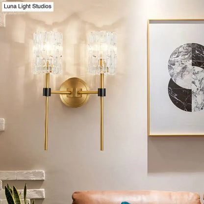 Minimalist brass wall sconce with gold tone, crystal cylindrical light fixtures, and black accents for living room use