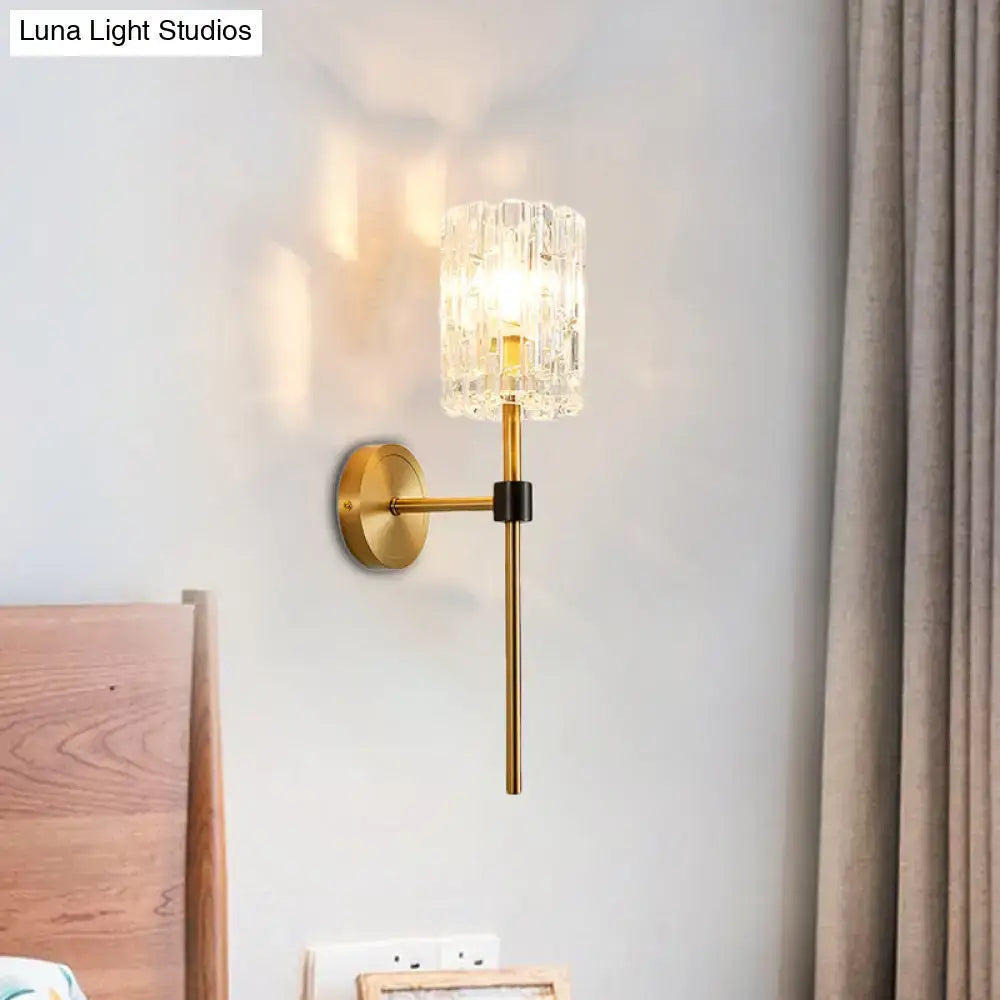 A minimalist brass crystal cylindrical wall sconce with gold metal arm for living room lighting