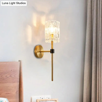 A minimalist brass crystal cylindrical wall sconce with gold metal arm for living room lighting