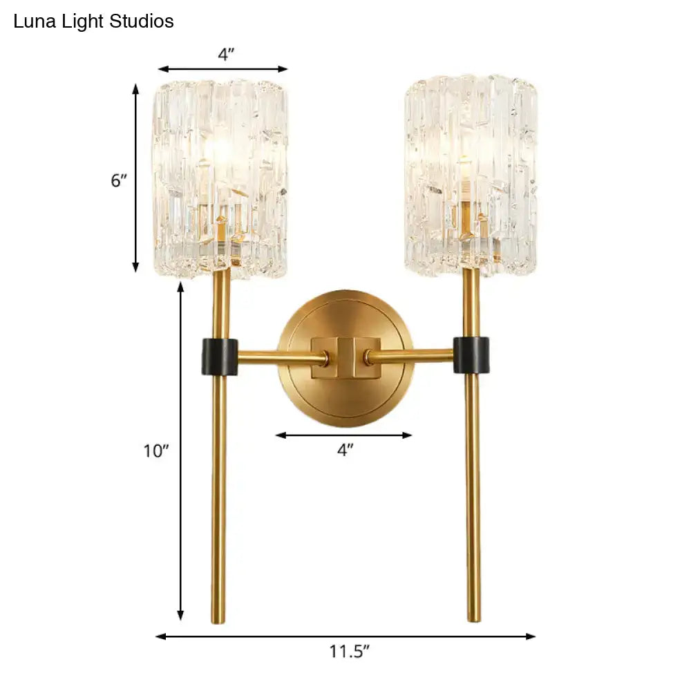 Minimalist brass crystal cylindrical wall sconce with gold-toned finish, textured glass shades, and black accents for living room