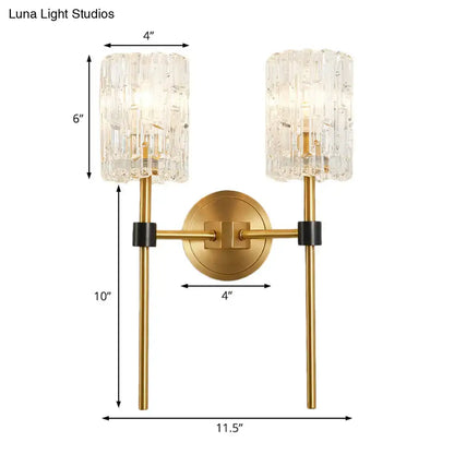 Minimalist brass crystal cylindrical wall sconce with gold-toned finish, textured glass shades, and black accents for living room