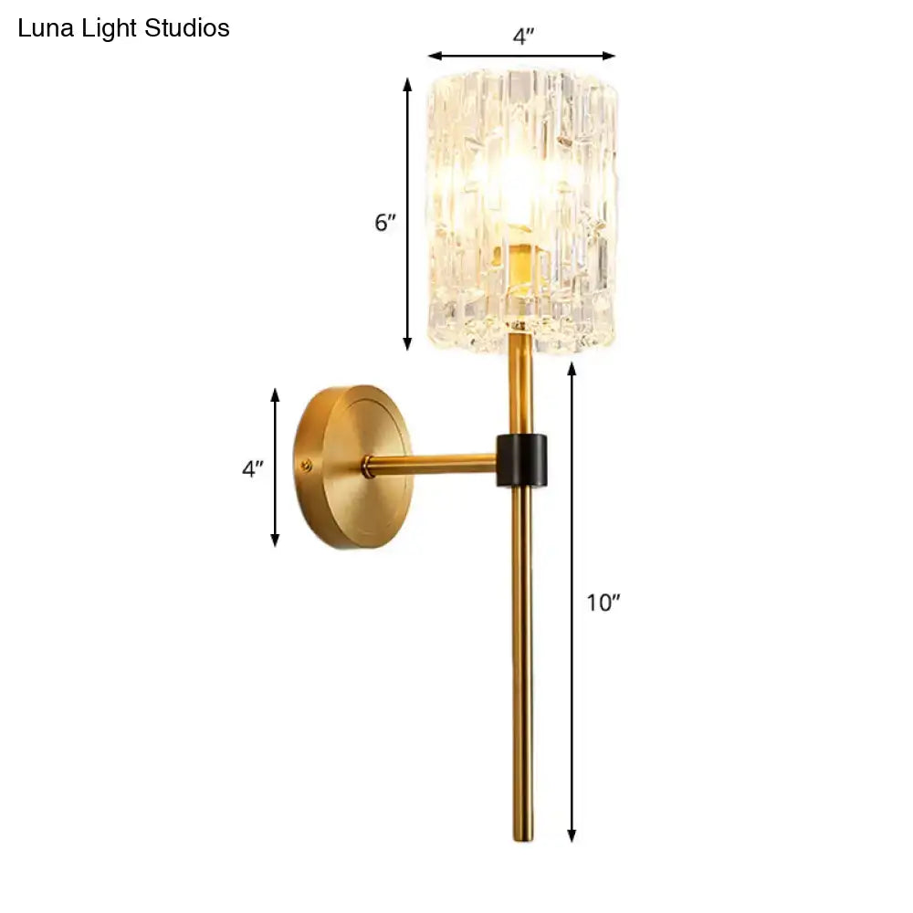 Minimalist brass wall sconce with gold metal base and crystal cylindrical glass shade for living room lighting