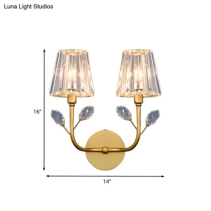 Minimalist gold-toned brass finish wall sconce with two crystal lampshades and leaf-shaped crystals on curved arms wall light