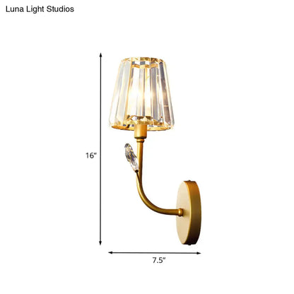 Minimalist gold-toned wall sconce with brass finish, faceted crystal shade, and ornamental bird accent wall light