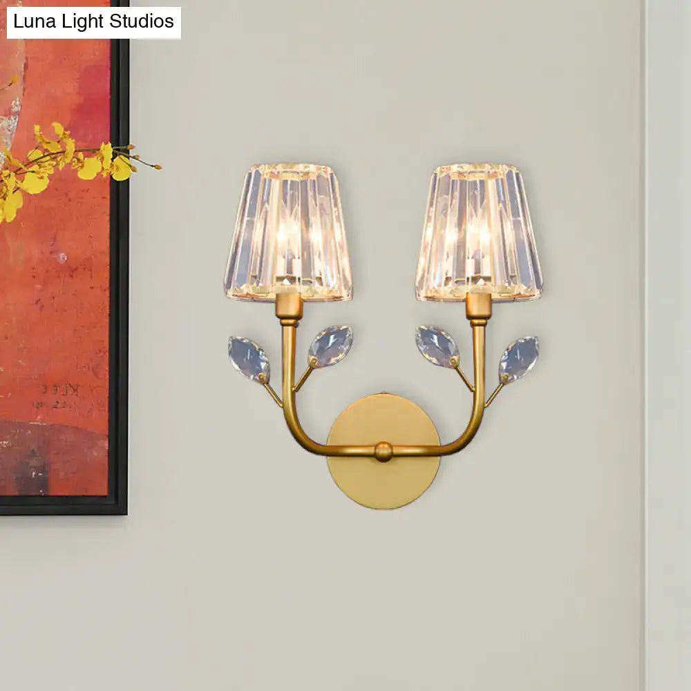 Minimalist gold-toned wall sconce with brass finish, faceted crystal shades, and leaf accents for bedroom wall light