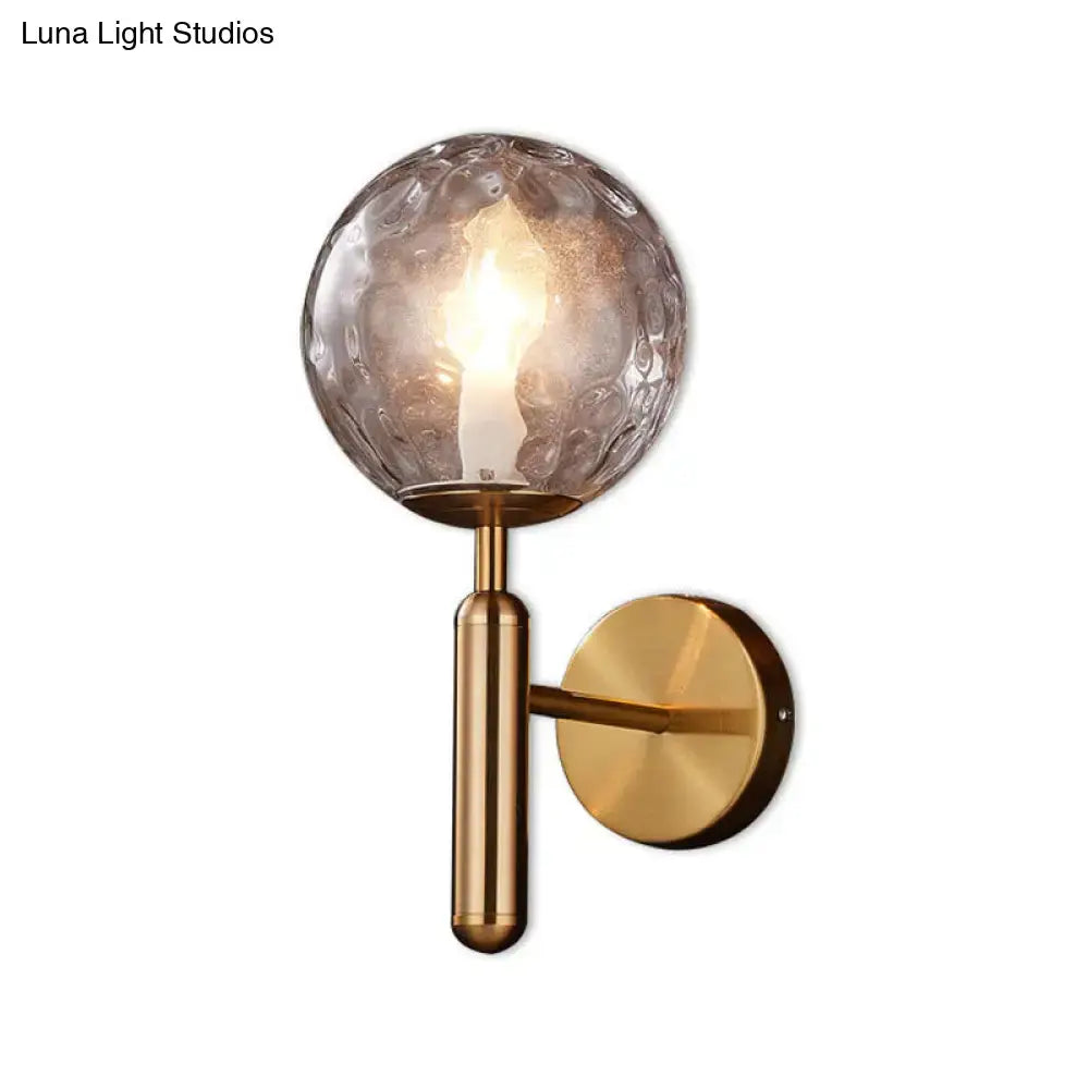 Minimalist brass wall mount light with gold-toned textured glass globe for bedroom lighting