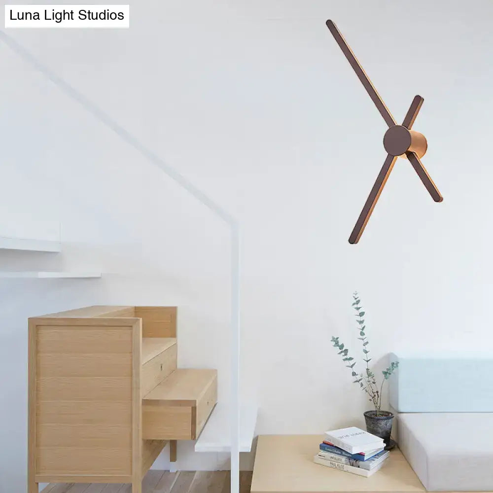 Minimalist wooden wall clock with dark-stained arms and circular hub paired with brass sconce wall light for living room