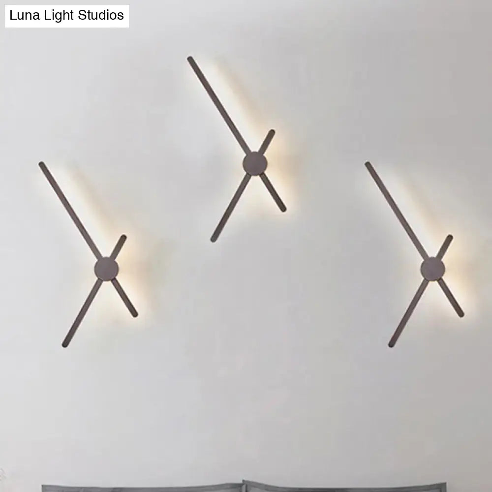 Minimalist brass sconce wall light with sleek matte metal arms providing warm ambient lighting for living room clock