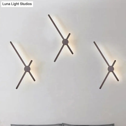 Minimalist brass sconce wall light with sleek matte metal arms providing warm ambient lighting for living room clock