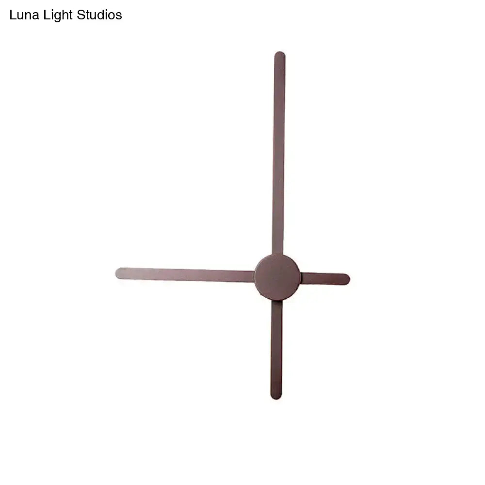 Minimalist brass sconce wall light featuring a matte bronze clock with slender geometric arms for living room use