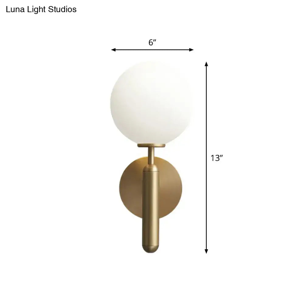 A minimalist brass wall sconce with a cream glass shade designed for elegant living room lighting