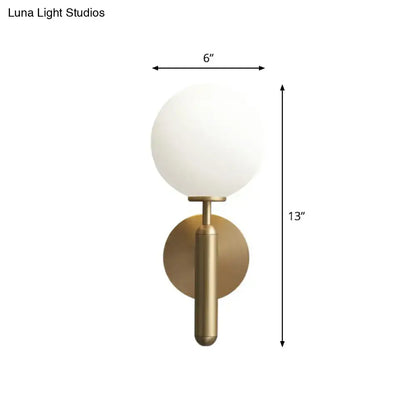 A minimalist brass wall sconce with a cream glass shade designed for elegant living room lighting