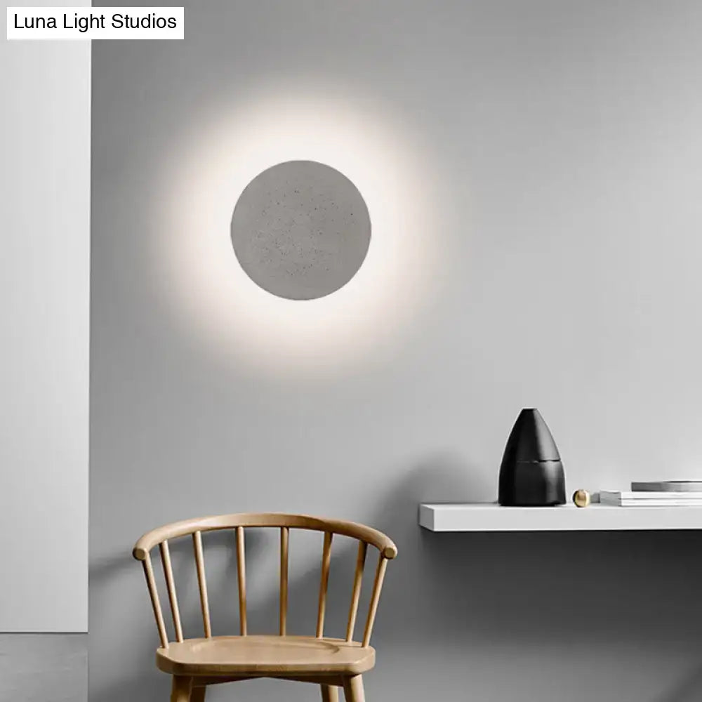 Minimalist cement grey flat round wall sconce light with circular concrete design and soft diffused glow for bedroom