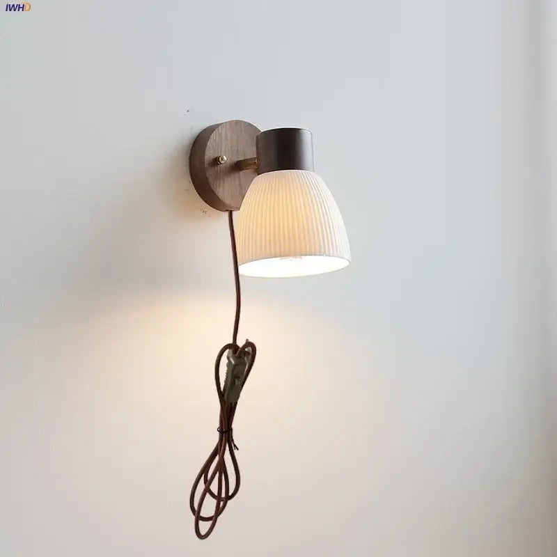 Minimalist ceramic walnut wood wall light with warm wooden base dark metal housing and off-white ribbed glass shade for reading