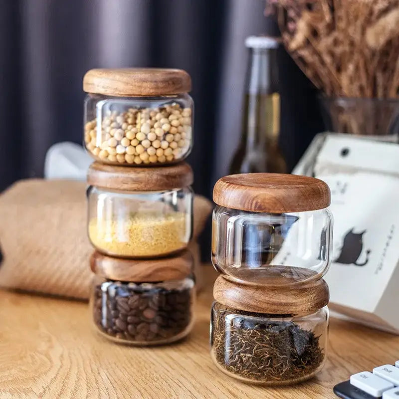 Minimalist clear glass storage jars with smooth rounded acacia wood lids for kitchen organization
