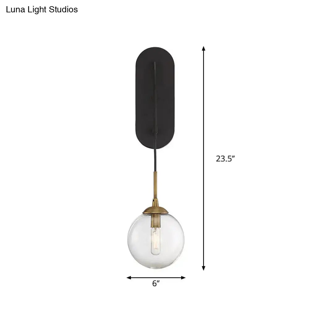 Minimalist clear glass wall mounted sconce with black base and brass finished stem for bedroom lighting