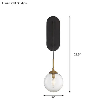 Minimalist clear glass wall mounted sconce with black base and brass finished stem for bedroom lighting