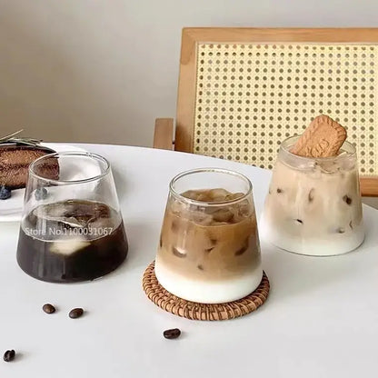 Three clear glass water cups filled with iced coffee drinks on a white table for kitchen and dining room use
