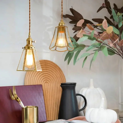 Two brass pendant lights with glass led hanging shades in triangular and fluted designs for minimalist kitchen use